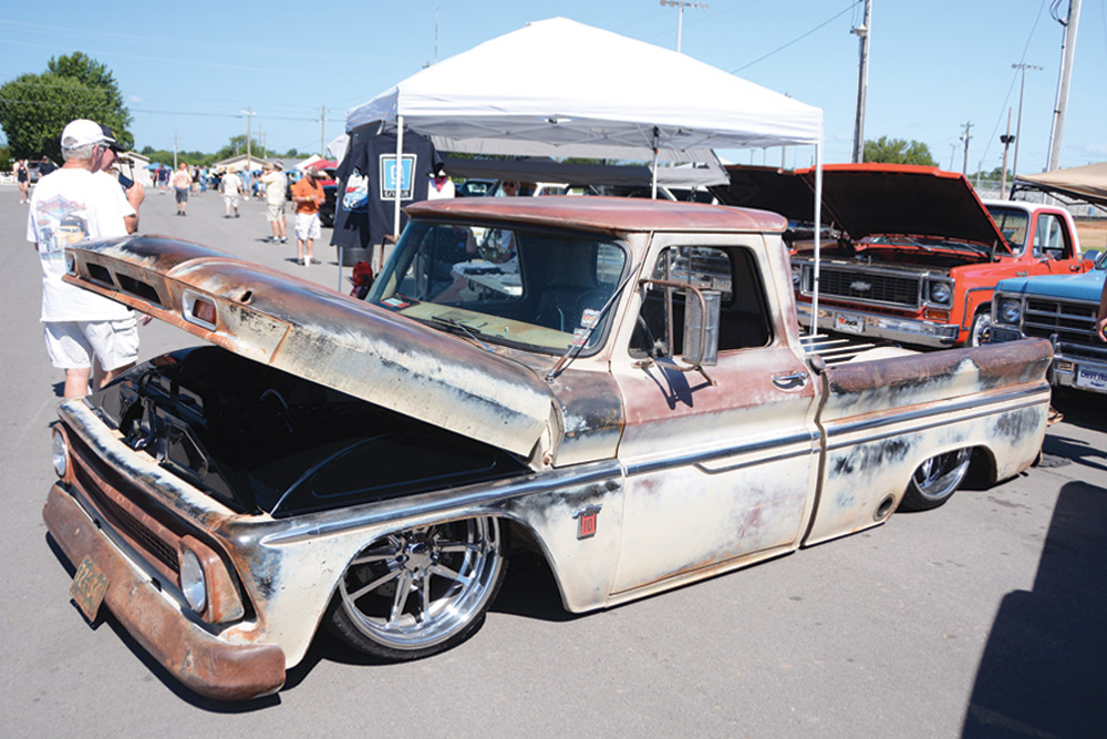 Slightly rusted, low-riding creme Chevy truck with hood open