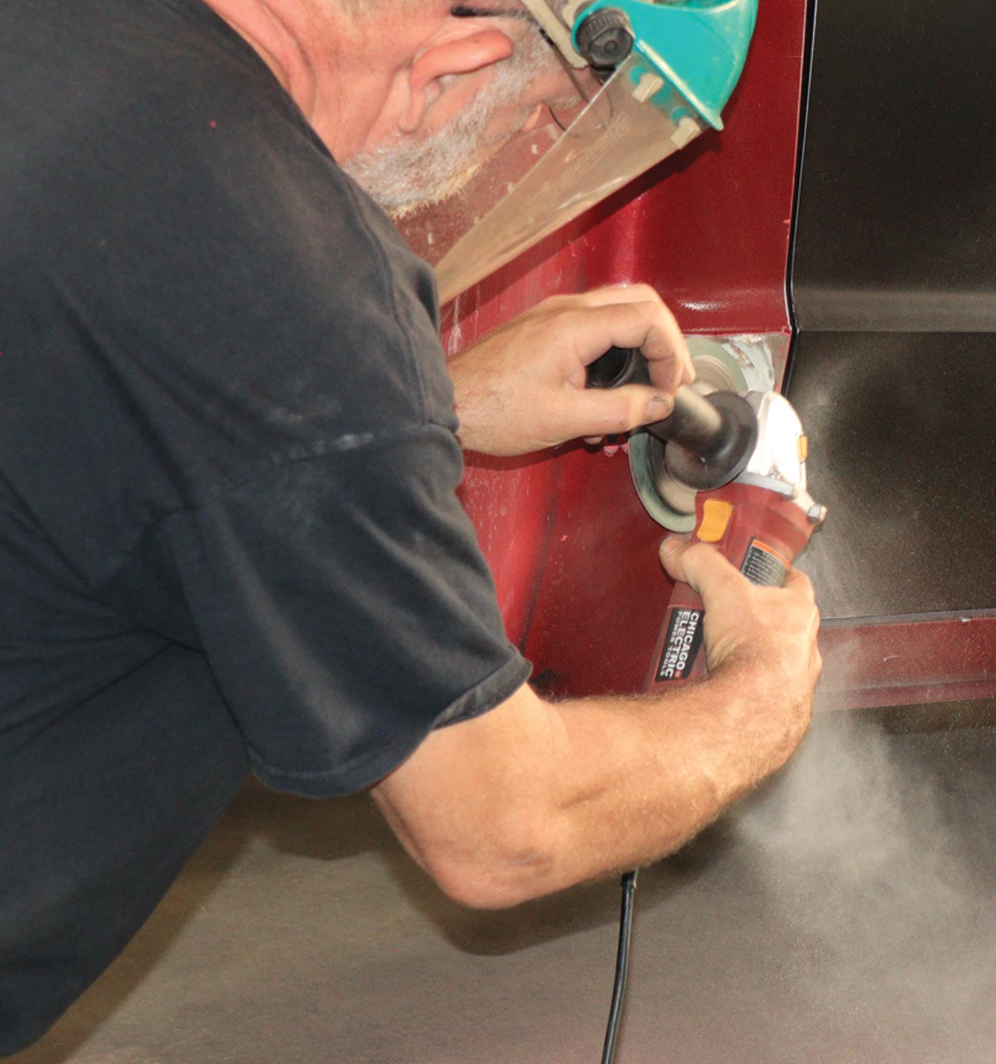 mechanic uses a tool to grind the paint from the existing cab corner