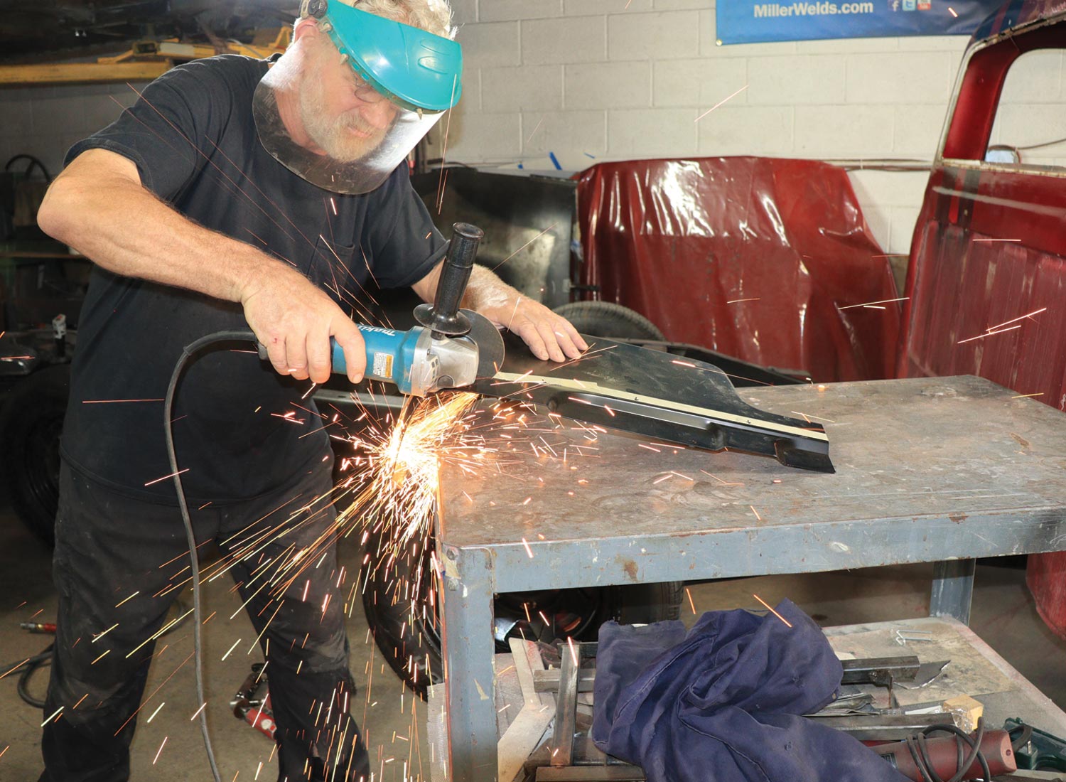 mechanic uses a body grinder with a 6-inch abrasive cutoff wheel on the previously installed replacement rocker panel