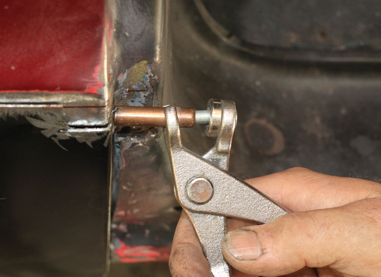 mechanic inserts a butt weld clamp in a cut made at the doorjamb