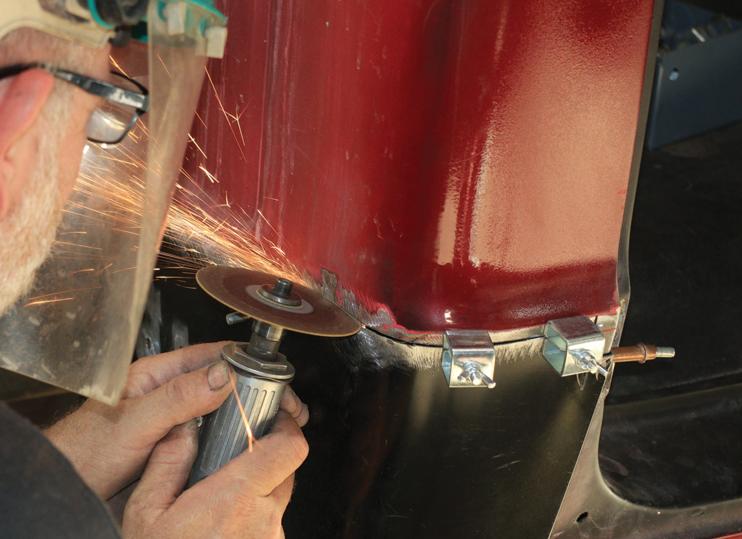 mechanic continues the cut made to the top line marked on the cab with a Sharpie using a 3-inch cutoff disc