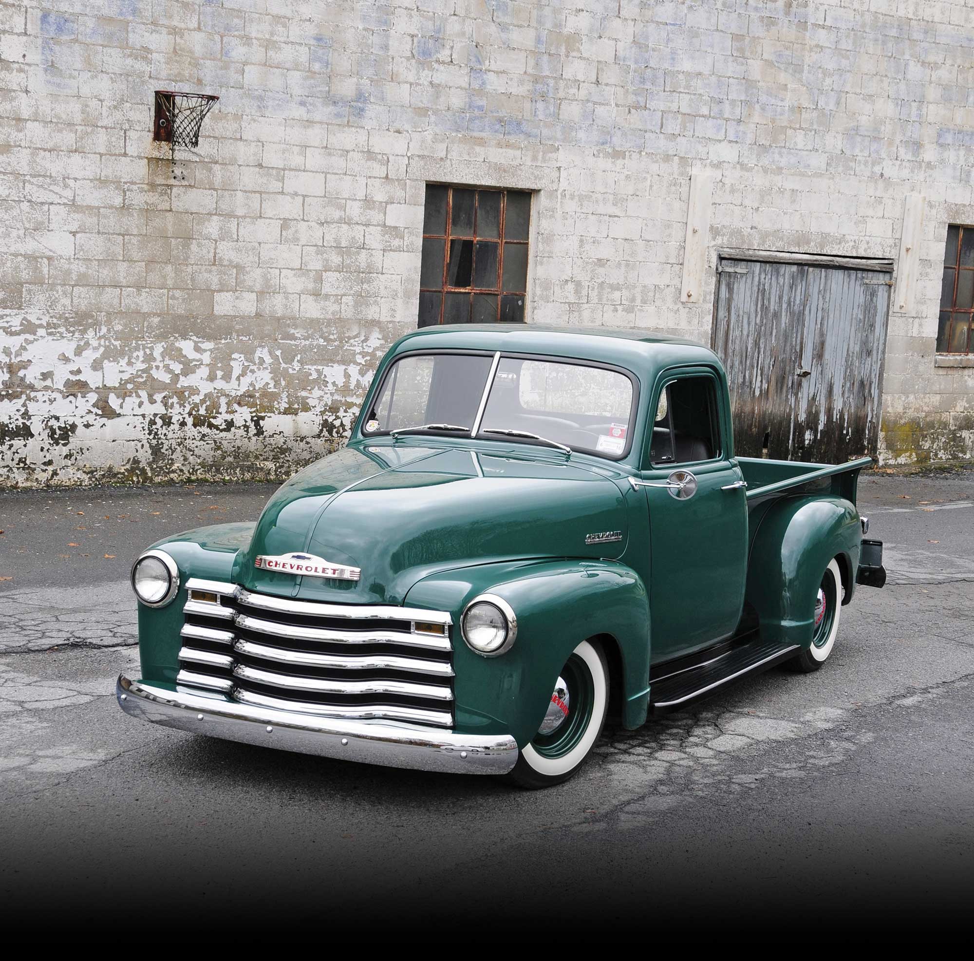 '52 Chevy front view with grey brick building in the background