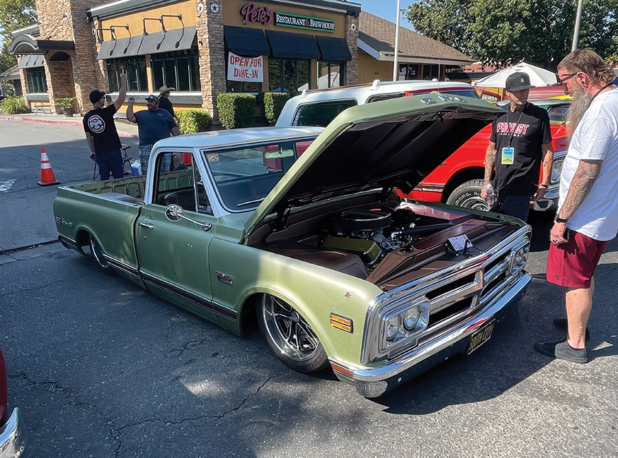 green truck with hood open and people taking a look