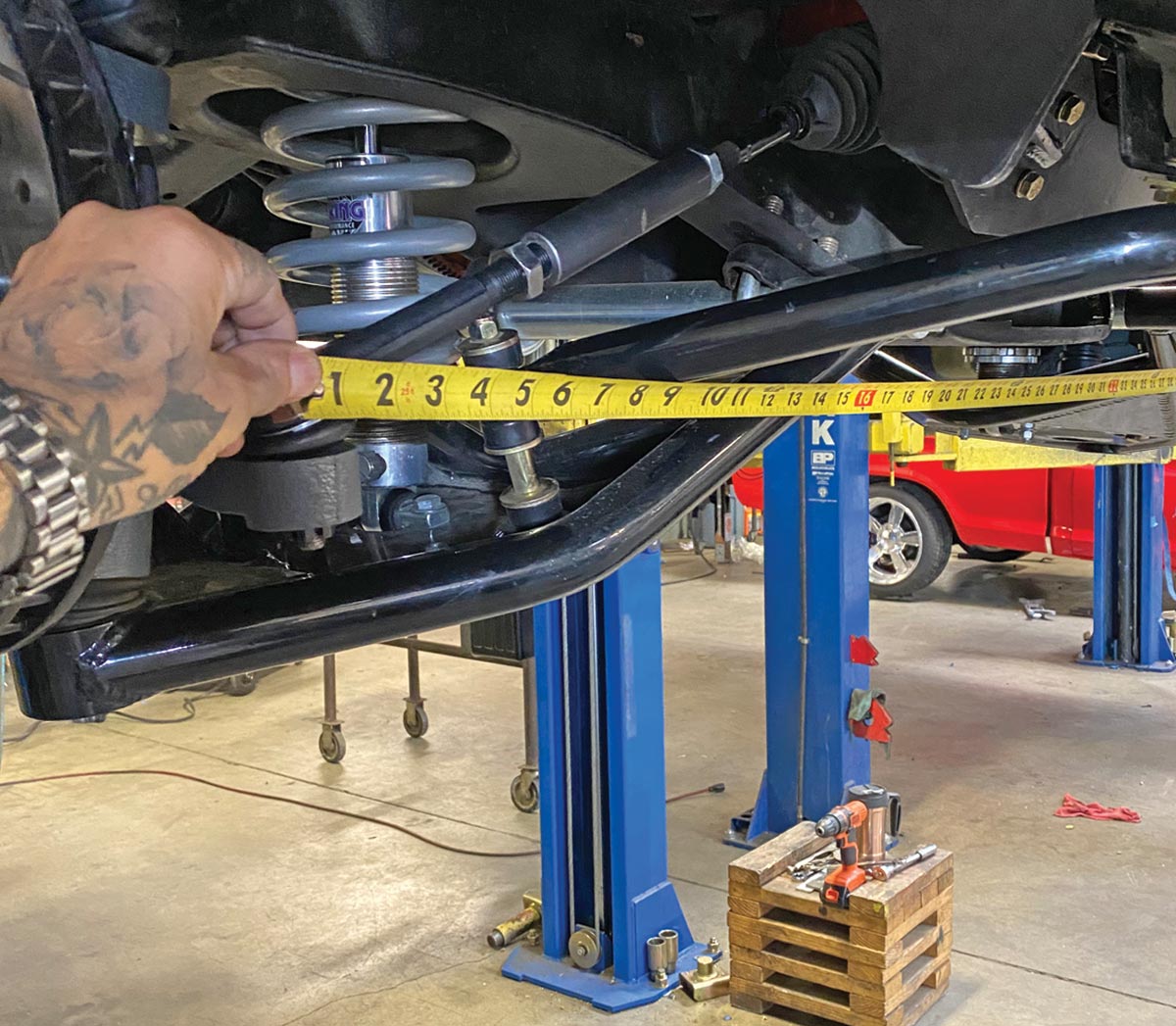 mechanic takes measurement beneath the truck