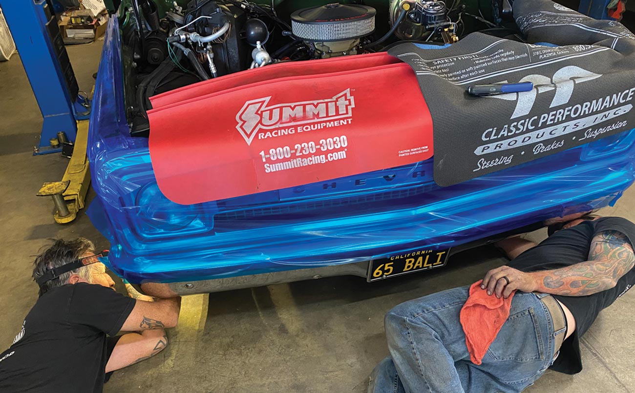 two mechanic lay on the ground working beneath the car