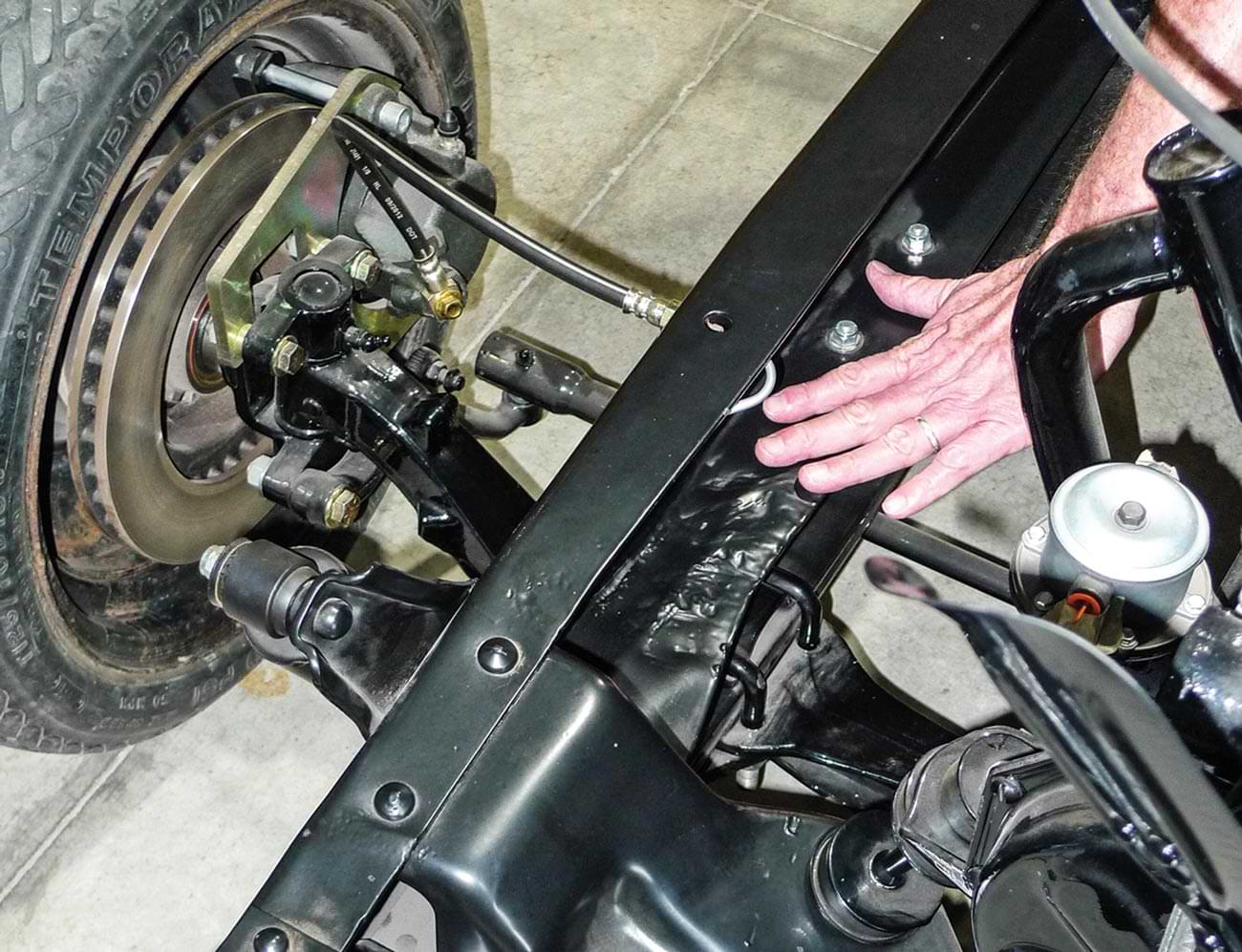 a hand references an area that was one bent on the car frame