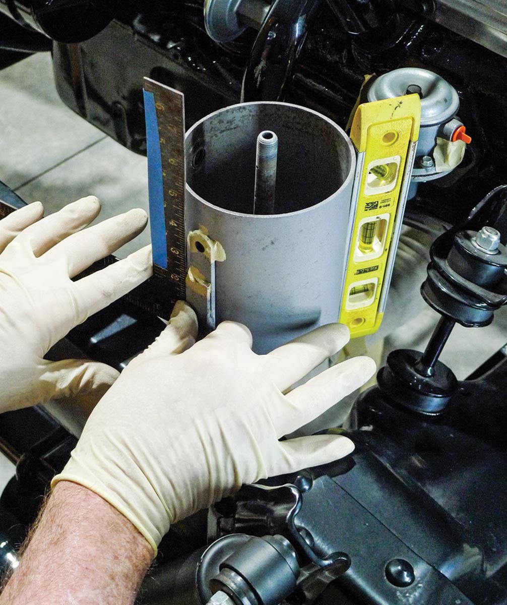 mechanic uses a level and square to determine the final placement of the can on the car frame