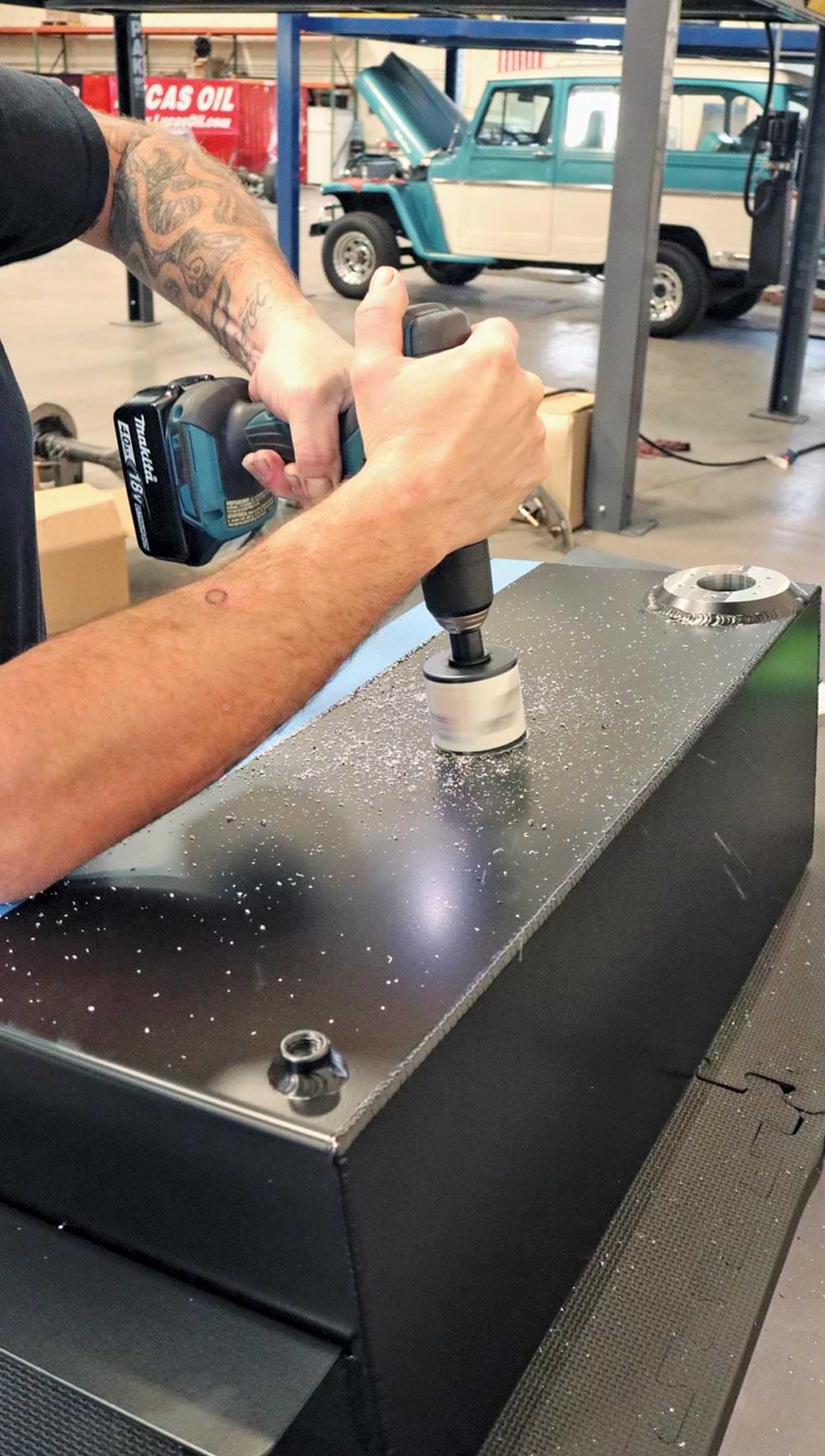 mechanic uses a 2-1/8-inch hole saw to make the pump hole in the tank