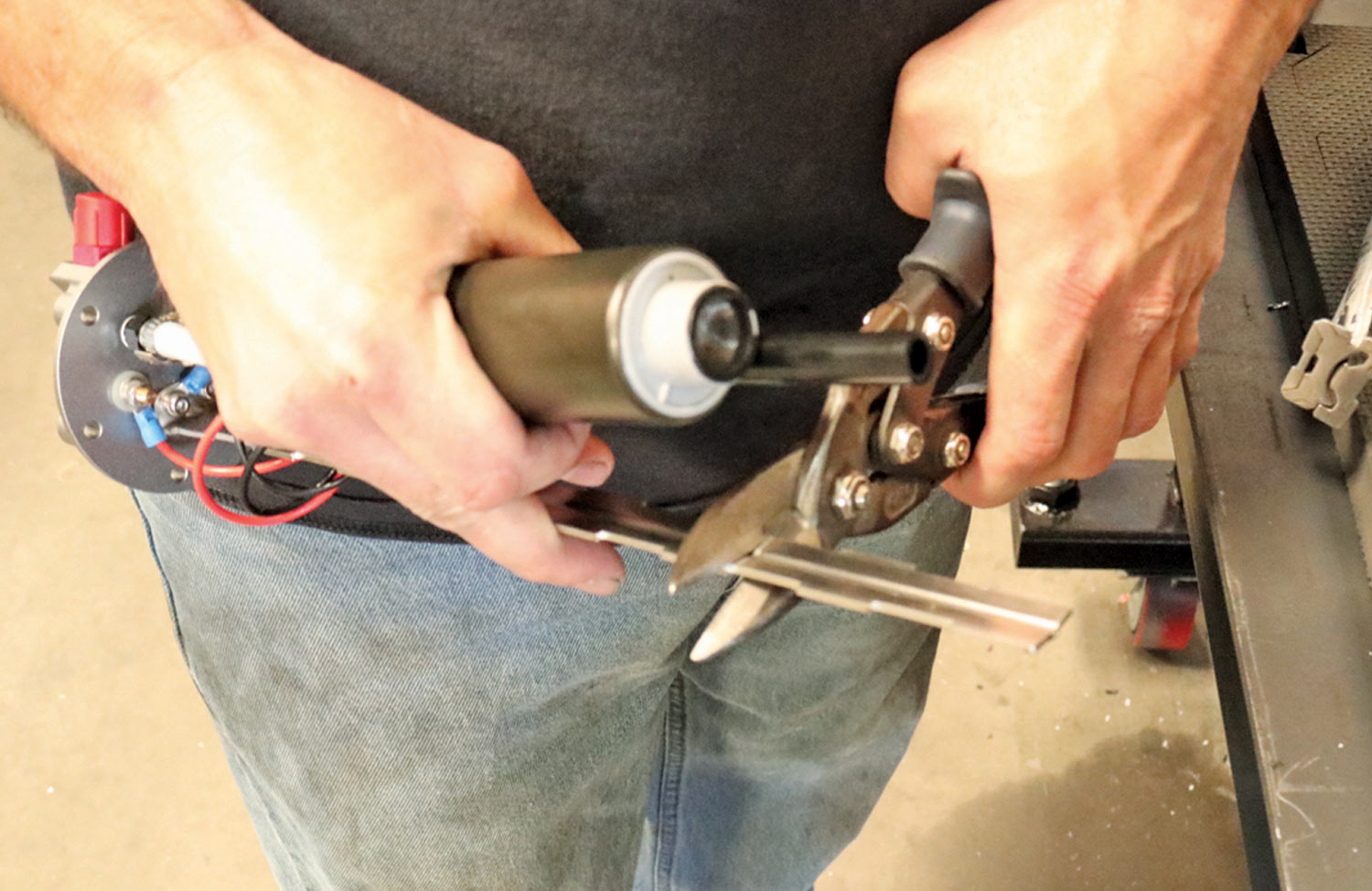 mechanic trims the metal support bracket on the pump part