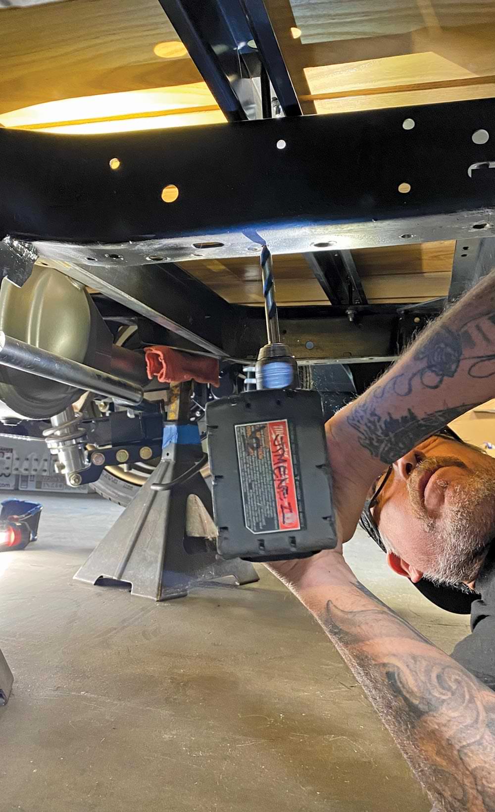 mechanic marks and drills the mounting holes for the tank beneath the car