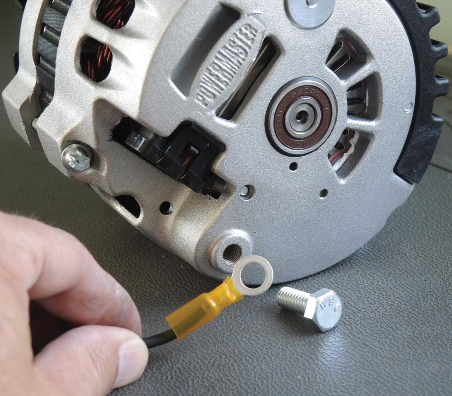 mechanic holds a grounding wire to the alternator