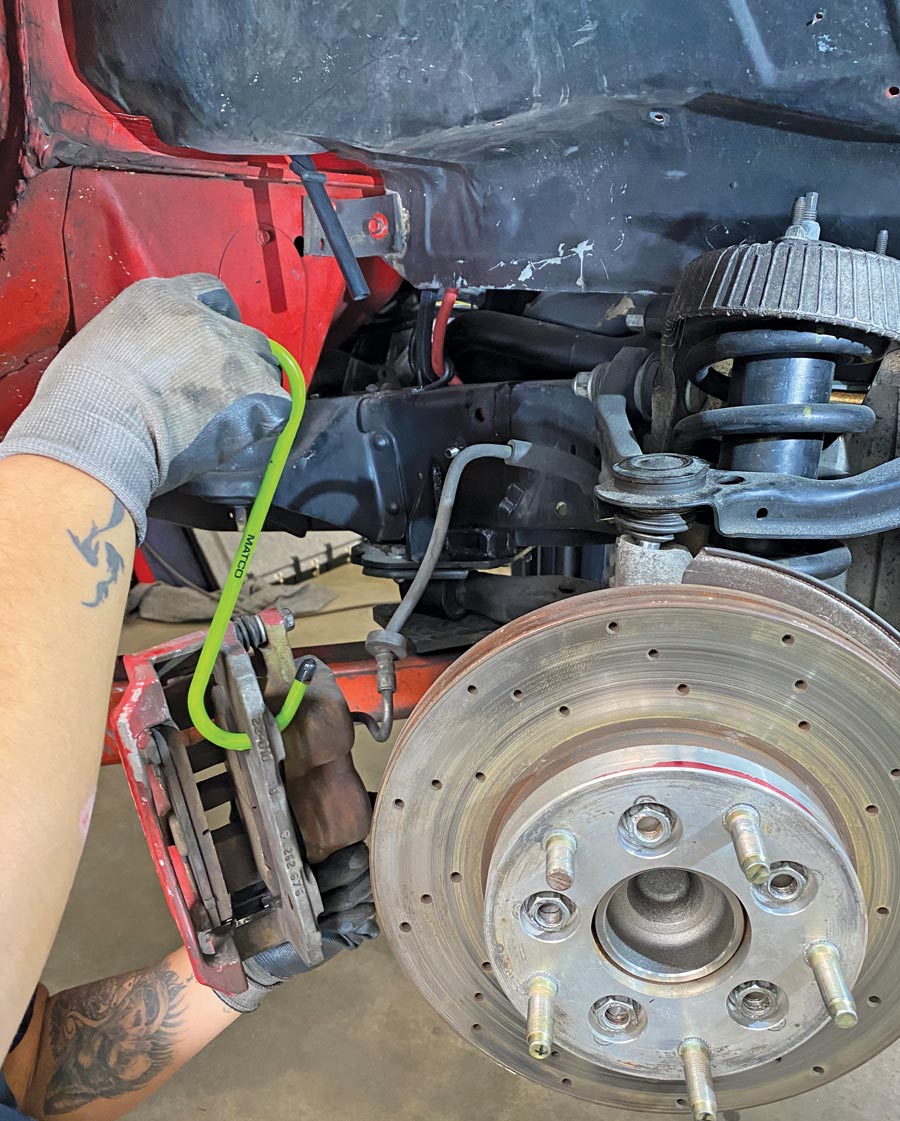 In preparation for the coilover swap, the disc brake calipers were unbolted and safely hung from the frame out of the way; the caliper will remain attached to the spindle for the procedure.