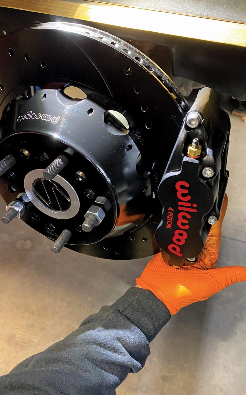 mechanic installs a black standard centered rear-side mount brake caliper to the rotor