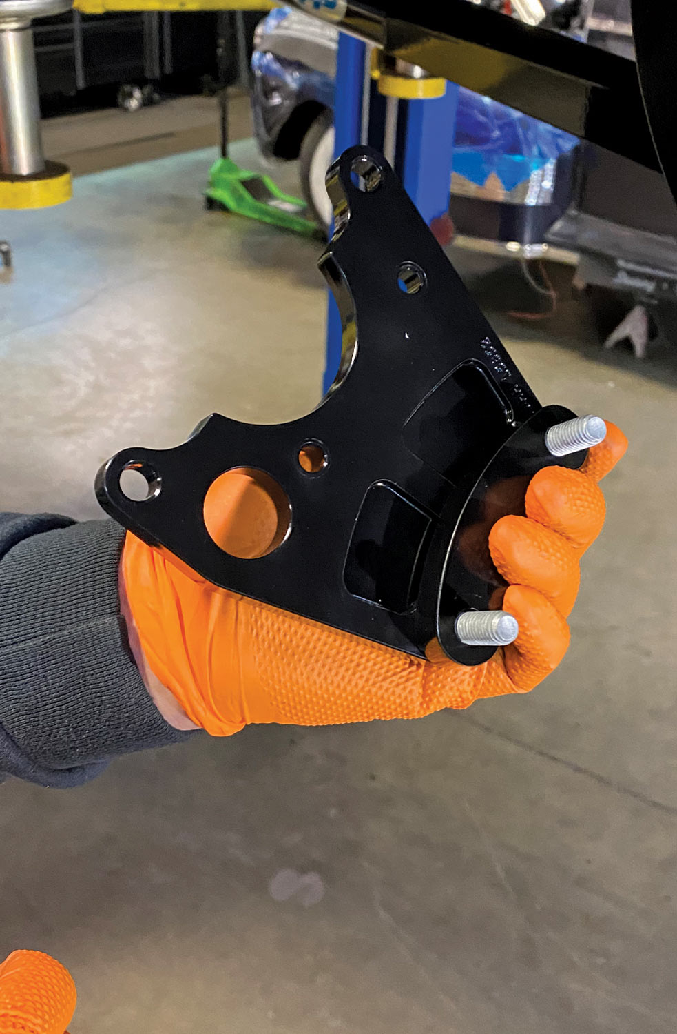 mechanic holds a part of the parking brake caliper in hand