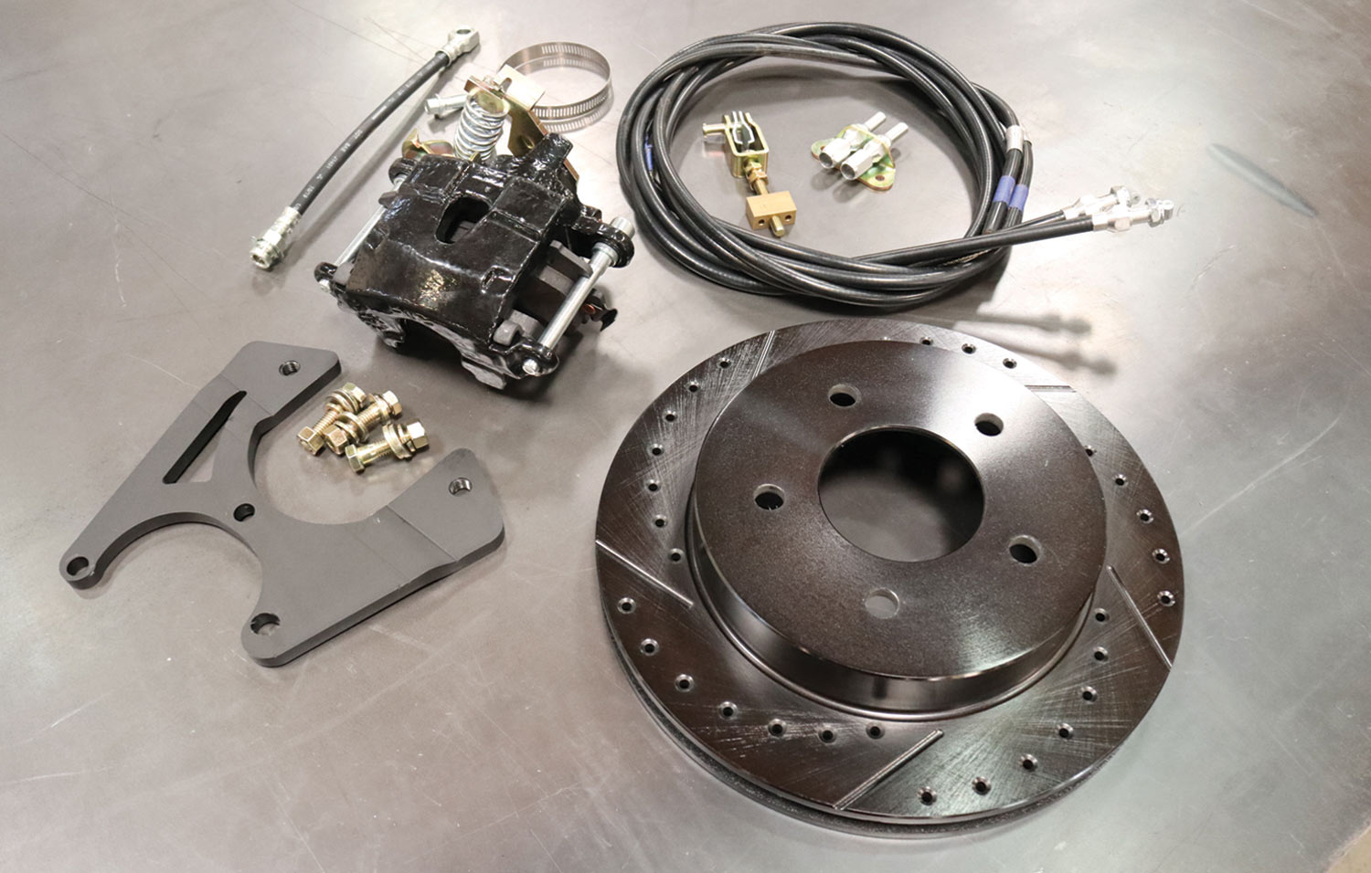 parts from Performance Online’s Blackout Series rear disc kit for the ’88-98 Chevy/GMC 1/2-tons (PN RWB58898) laid out, including a set of coated, drilled-and-slotted 11.75-inch rotors, parking brake–equipped GM single-piston calipers with laser-cut brackets, rubber flex hose, and trim-to-fit parking brake cables
