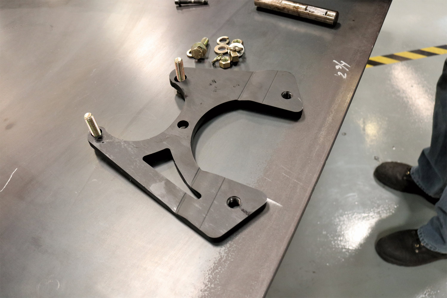 a supplied rear-facing caliper bracket sits on a work surface waiting for installation