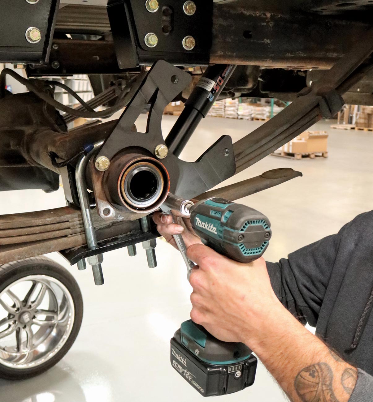 mechanic uses a drille to tighten a nut on the axle