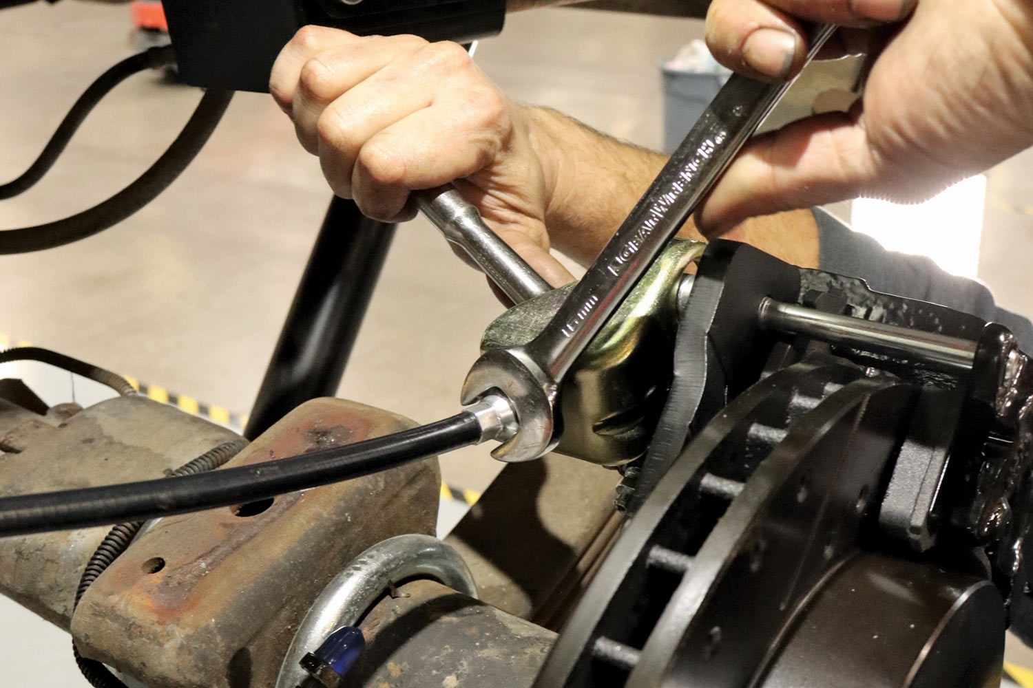 mechanic installs the cable rear ends into the caliper’s parking brake lever