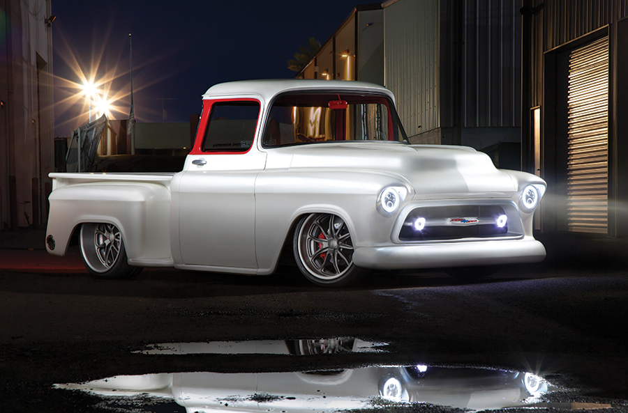 white '57 Chevy at night with headlights on