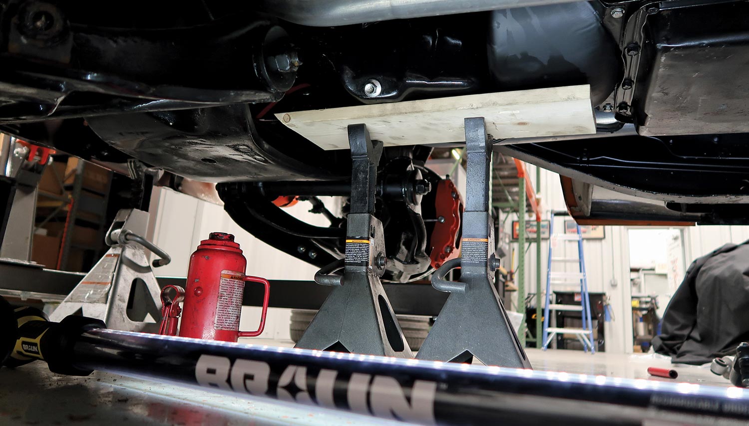 view under the car of the engine supported by a wood block on a pair of jackstands