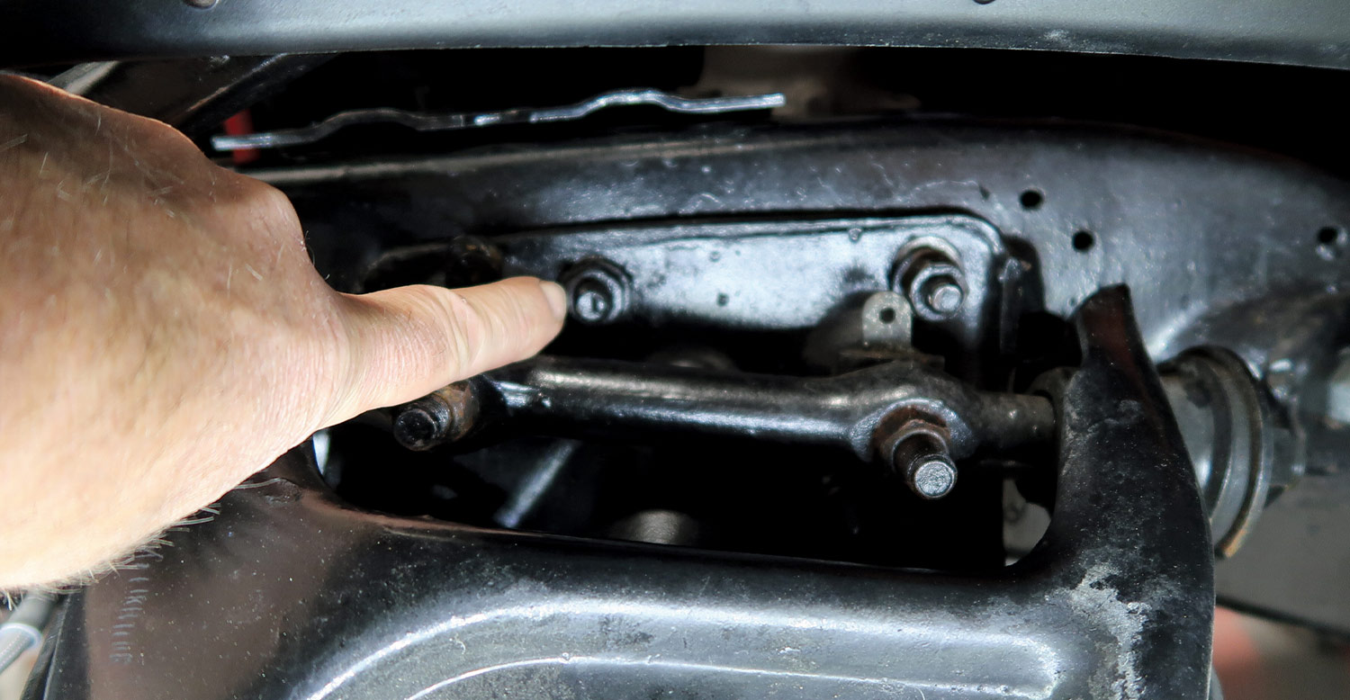mechanic points to a bolt on control arm
