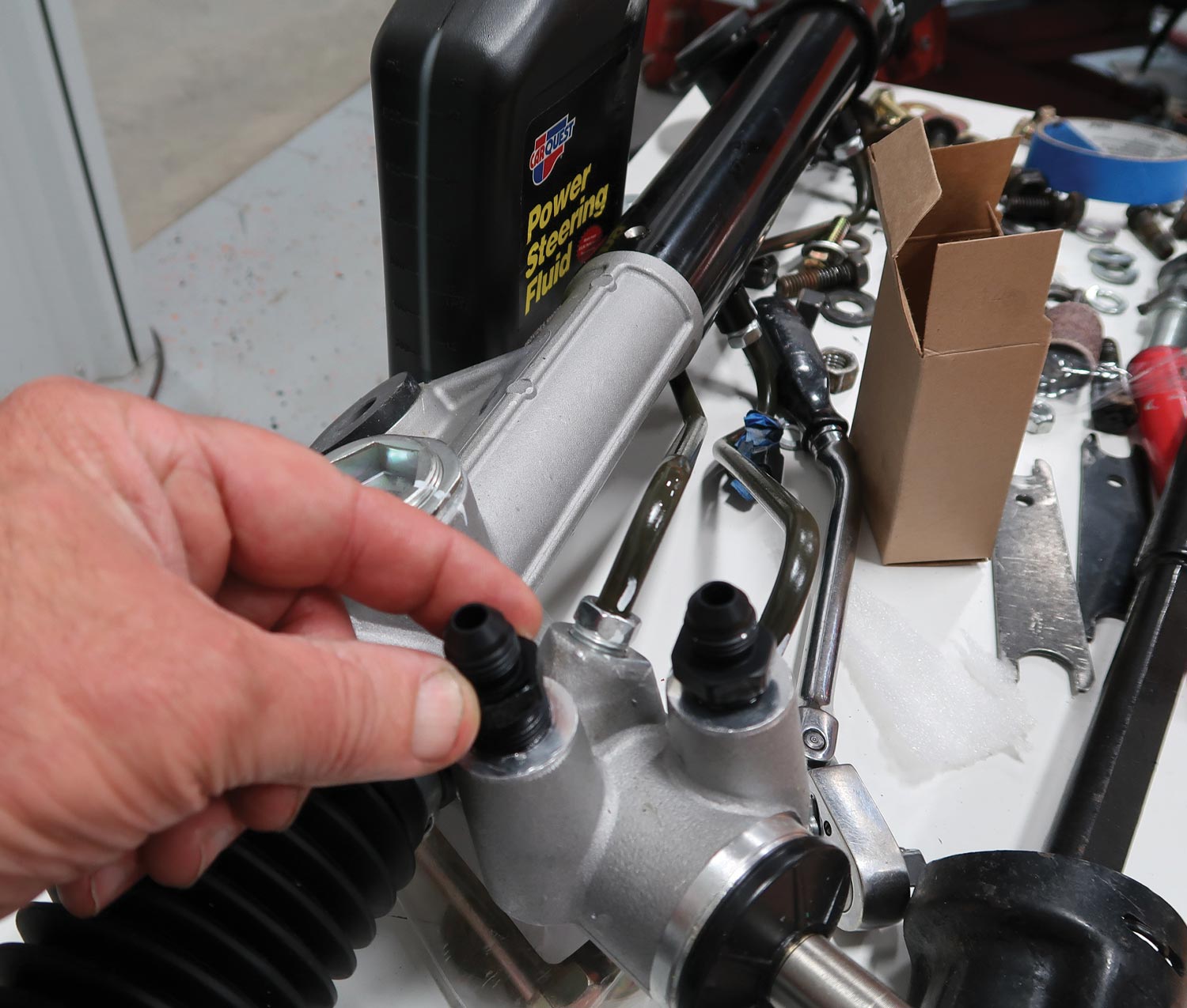 mechanic installs the adapters for the power steering hoses