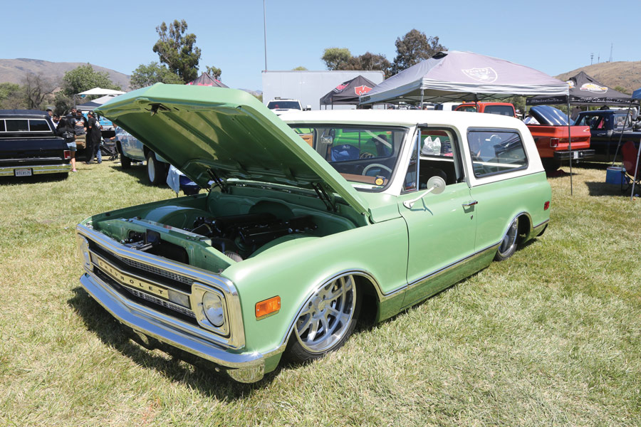 light green truck with hood open and a white camper shell