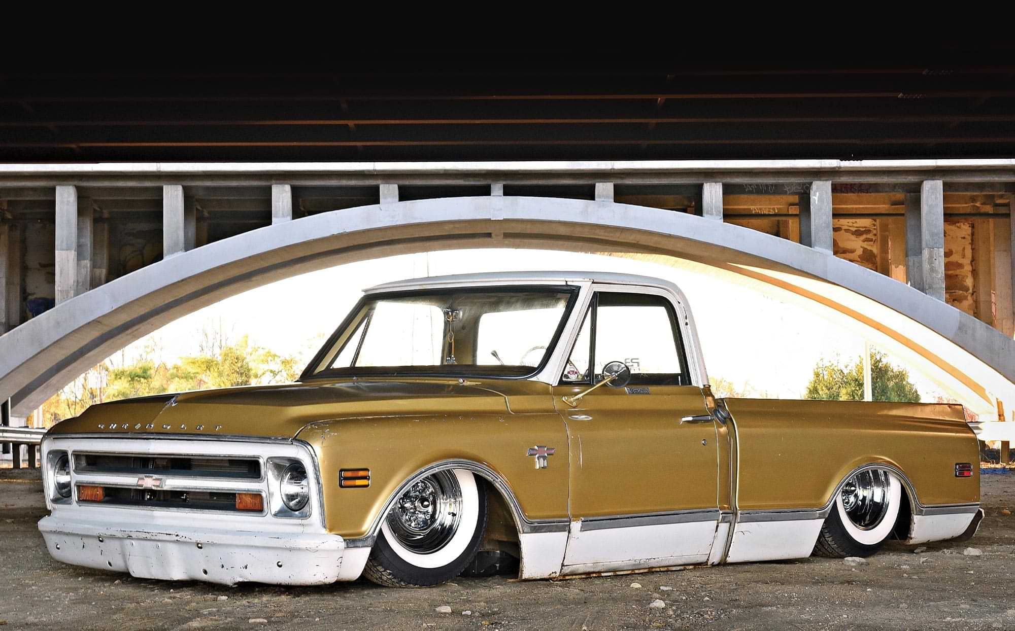 three quarter view of Phill Cann's Lo-Fi-Styled '68 C10 shortbed truck in gold and ivory, parked near an arching overpass