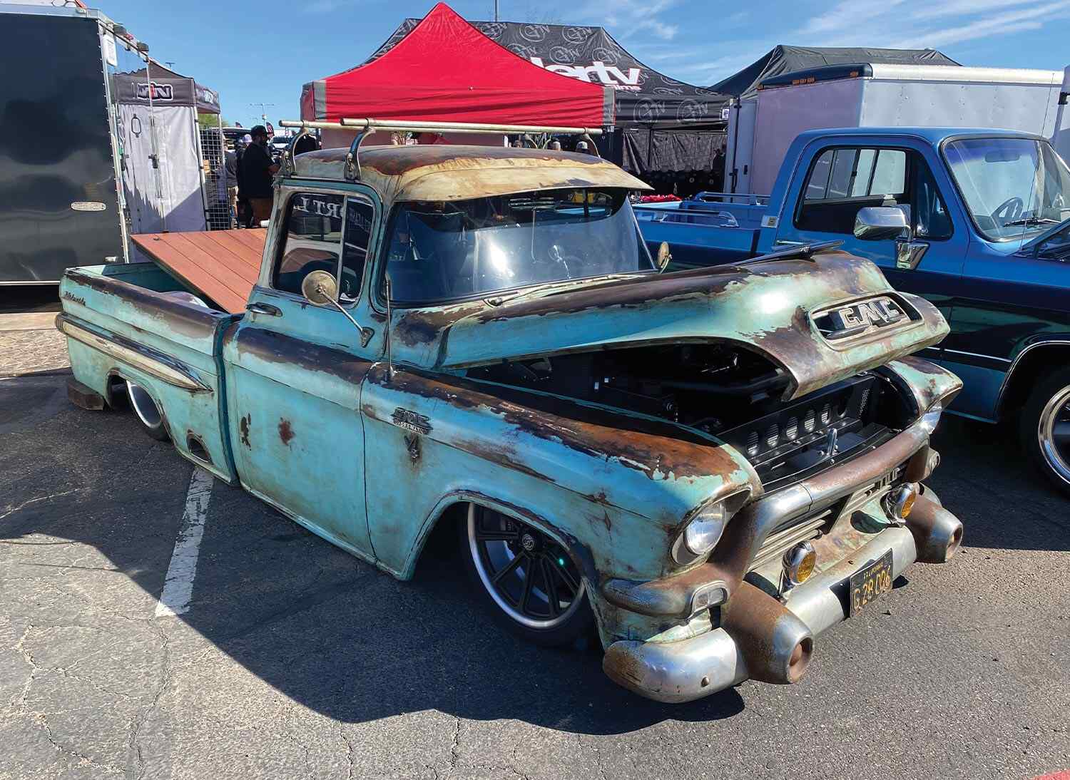 three quarter passenger side view of a teal patina GMC classic truck with its bed and hood slightly raised