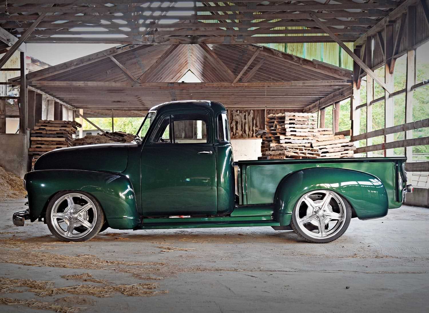 driver side profile of the limerock green Chevy 3100 parked beneath a large tattered wooden structure