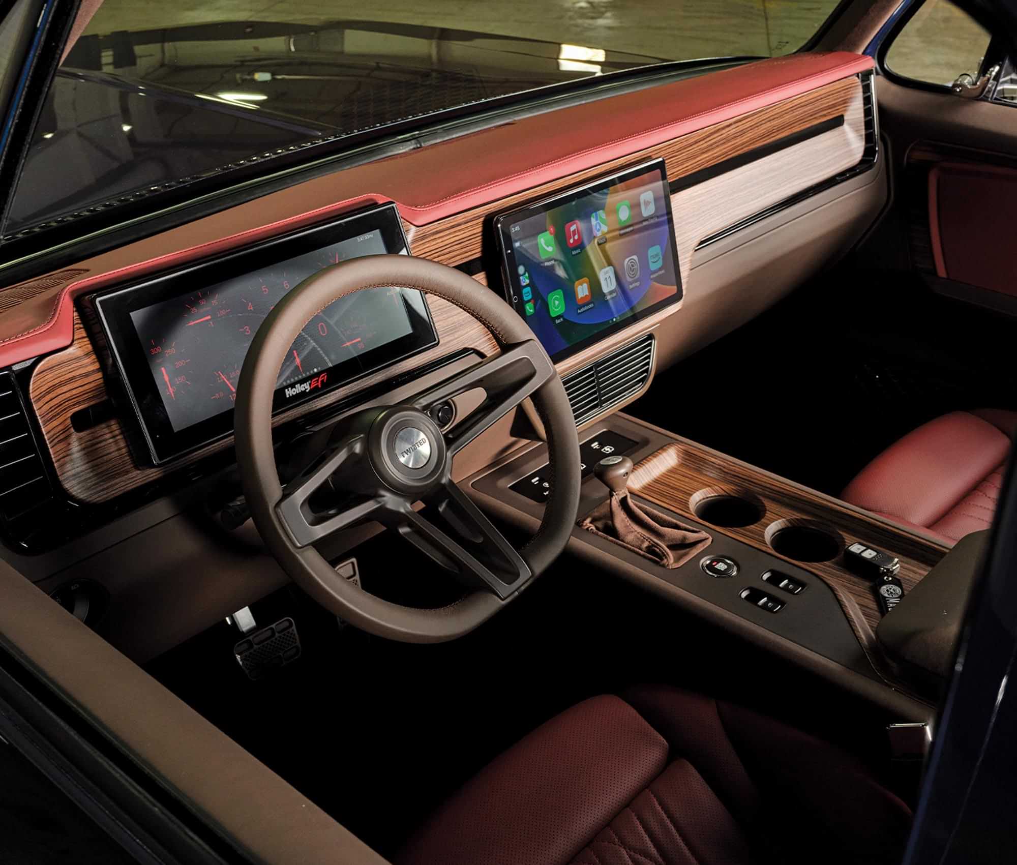 wide view of the red and brown leather lined Jimmy dashboard including a Holley Performance 12.3-inch Pro Dash, the Linkswell 13.3-inch head unit, the Vintage Air A/C system, and a custom-finished Sparc Industries steering wheel