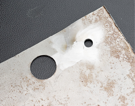 The small 5/16-inch hole is typical of the holes in his pickup that will be plugged. The first step was to clean the surface with an abrasive disc.