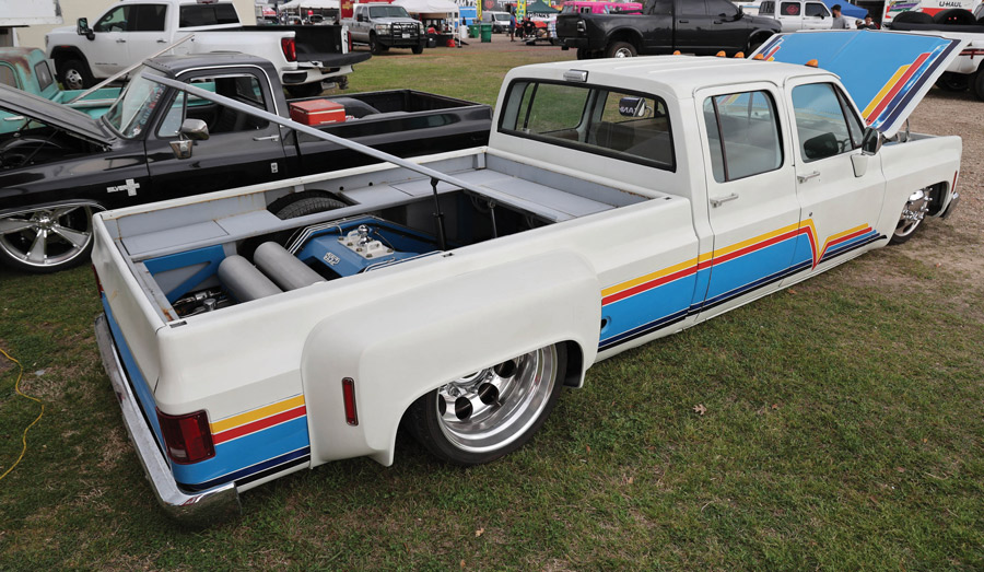 white truck with stripes on the side that are yellow, red, light blue, dark blue, and black