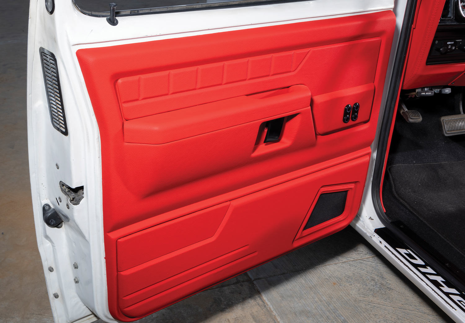 view of the ’89 Dodge Ram D150's open driver side door featuring vibrant red lining