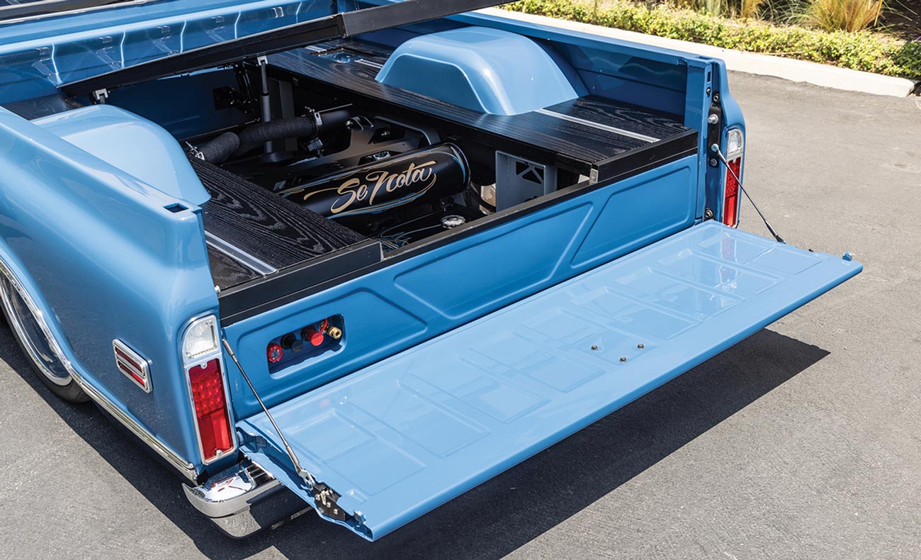 3/4ths view of the '70 Chevy C10 bed with the a section of the raised bed floor lifted to display the rear suspension components