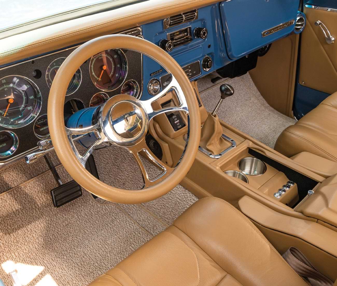 wide view of the drivers dashboard including the steering, gauges, pedals, radio and center console