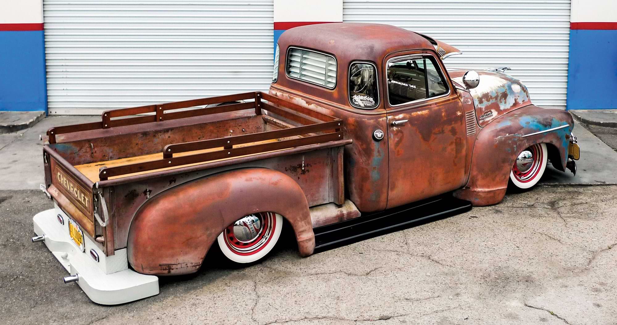 rear side angle view of chevy truck with rusty paint job
