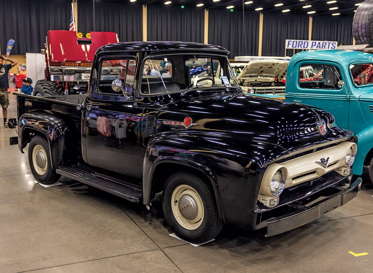 A spectator glances at the black and blue shiny vintage Ford F-100 cars on display inside the 2023 Grand National F-100 Show in Pigeon Forge, Tennessee