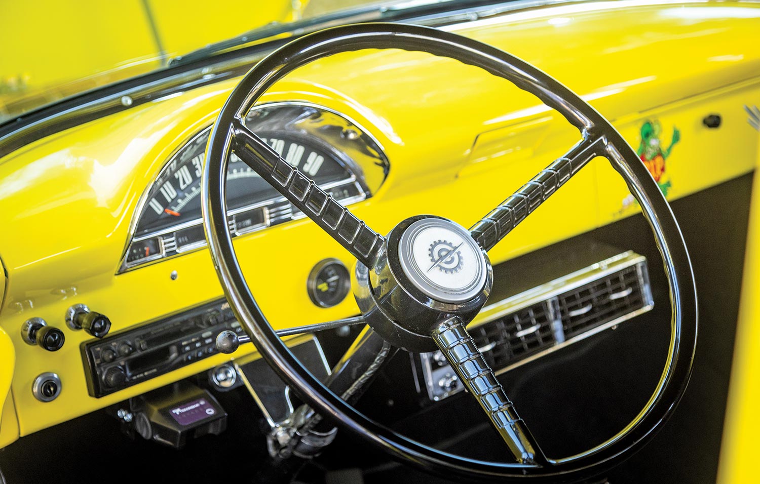 view from outside the driver side window of the classic large steering wheel and dashboard of the ’56 Ford F-100