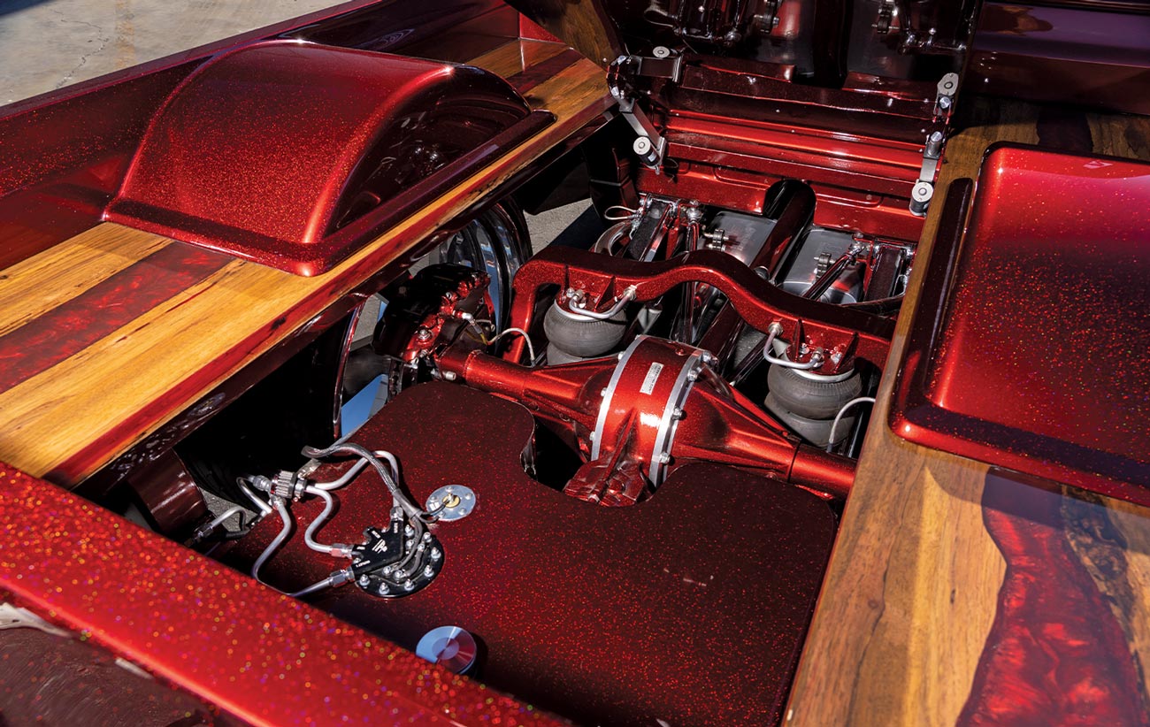 view of the ’68 Chevy C10 with the center panel power lifted to display the trucks rear suspension and glittering ruby red chassis