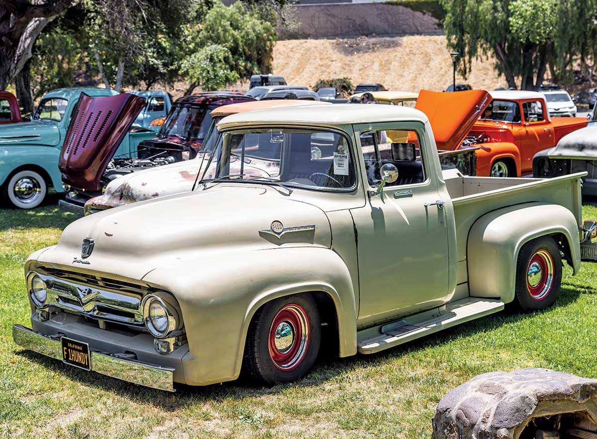 Landscape close-up photograph perspective of a faded tan vintage Ford F100 vehicle parked on the grass next to other vintage Ford vehicles at Canyon RV Park in Anaheim, California