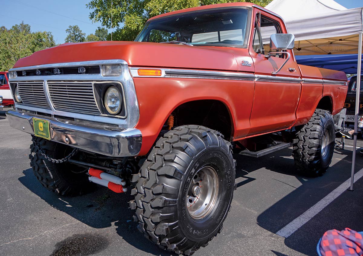 Close-up landscape photograph angle perspective of a red-colored Ford vintage vehicle parked in a parking lot area underneath a white tent