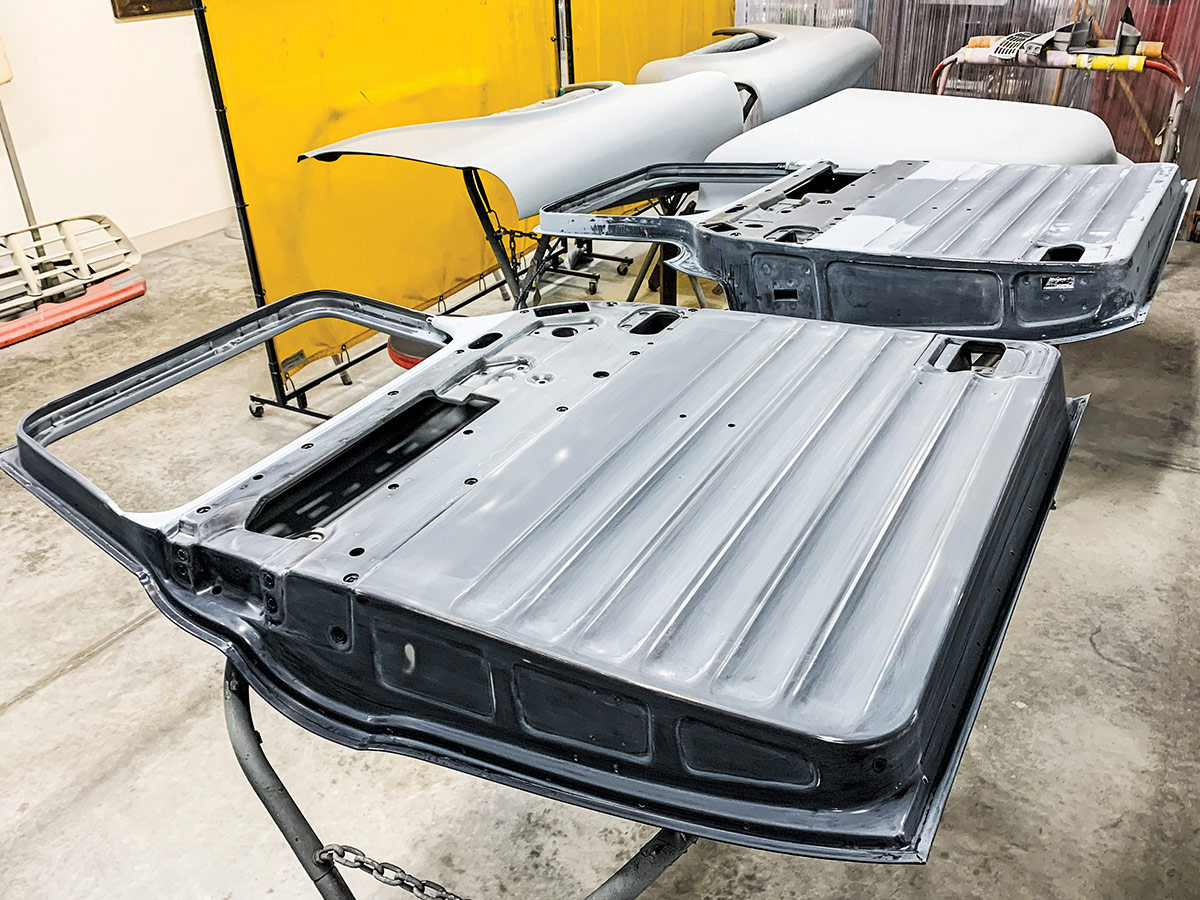 Two unpainted car doors with no interior panels laying on a stand