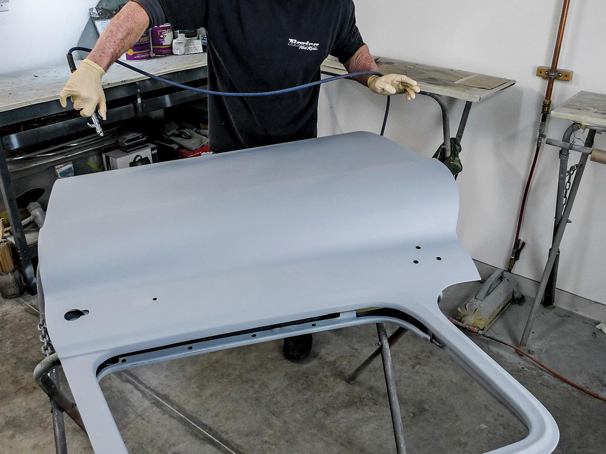 Man using a tool to blow dust off the unpainted car door