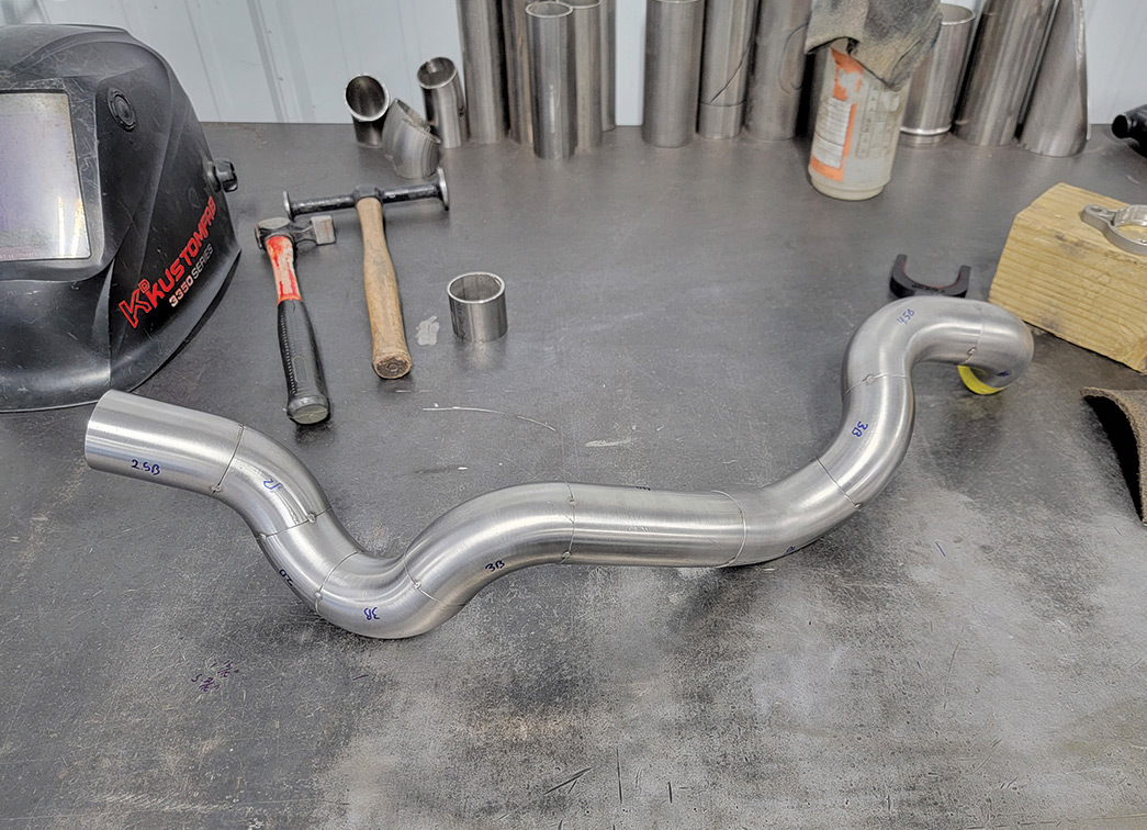 Header tube laying on table with tools around it