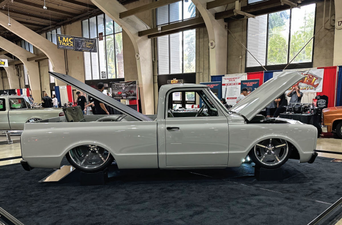 passenger side profile of off white lowrider classic truck with trunk hood and front hood propped open