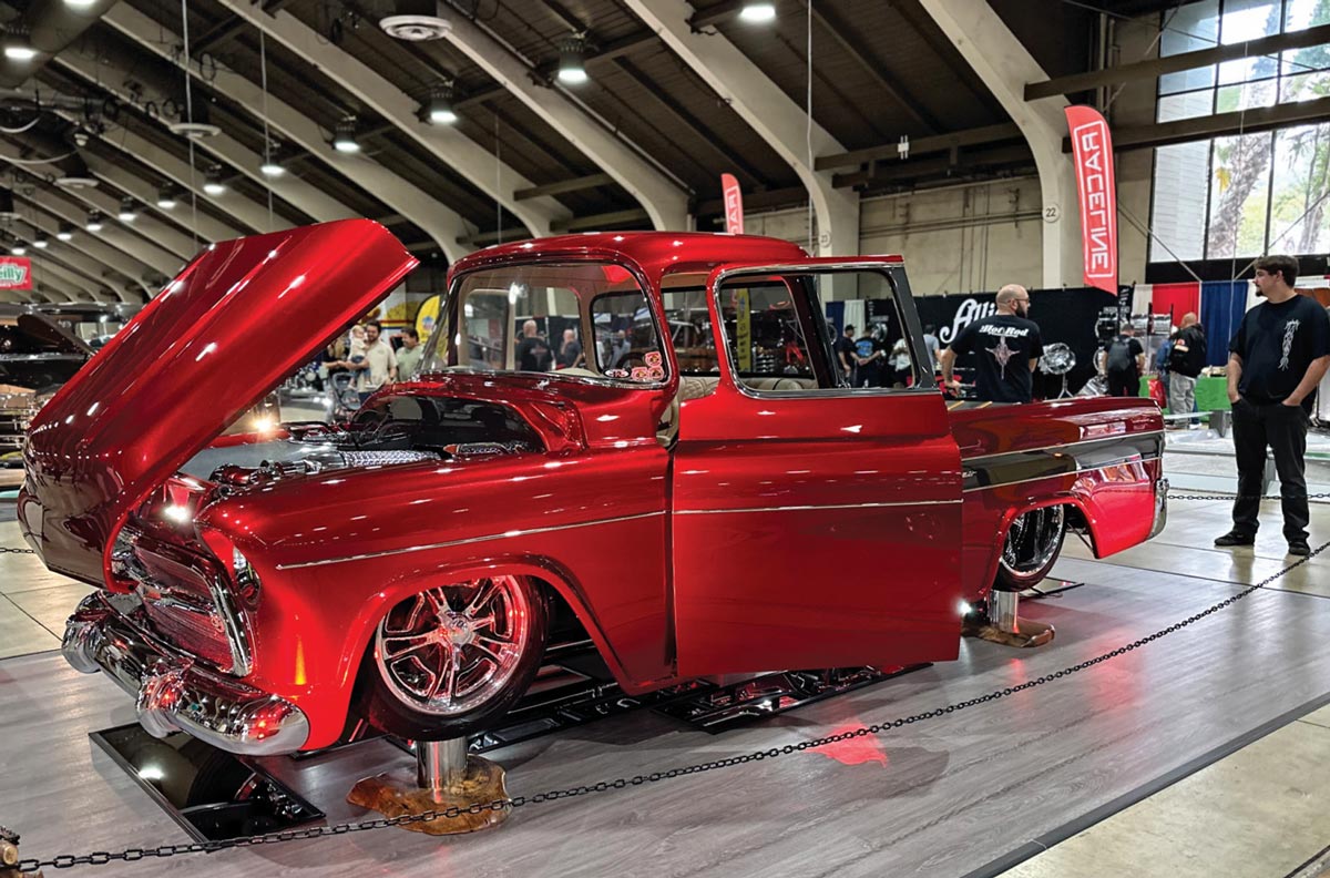 driver side quarter view of a ruby red classic truck with its front hood and doors open