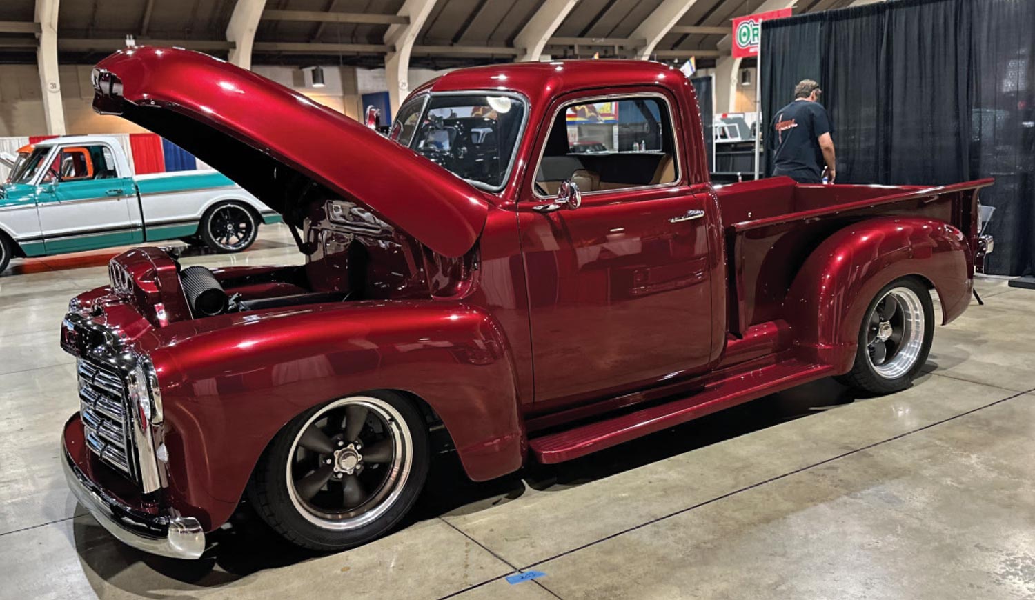 driver side quarter view of a ruby red classic truck with its hood open