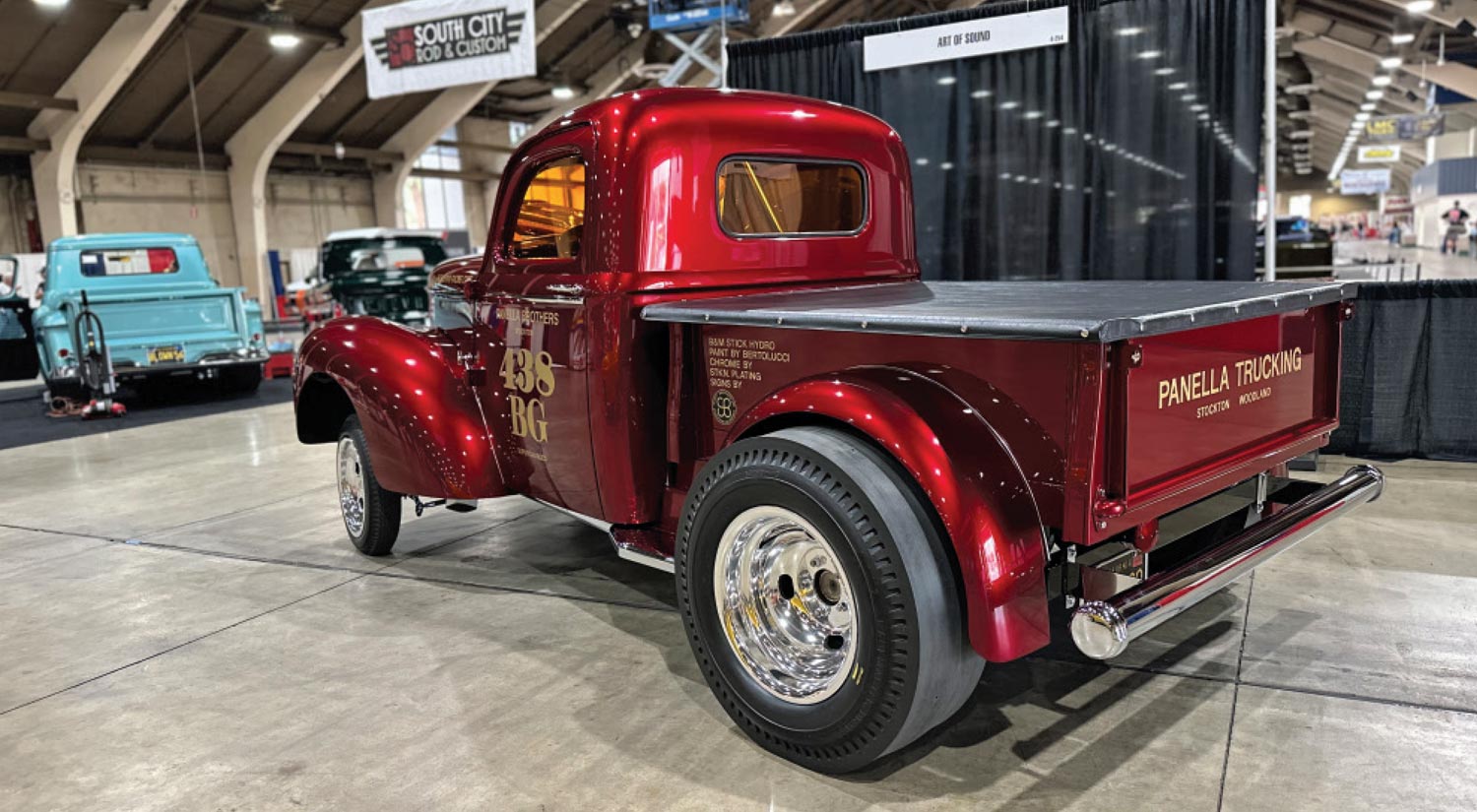 driver side rear quarter view of a ruby red classic truck with gold typography