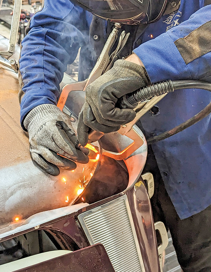 Man wearing a welding mask and gloves, welding the two panels